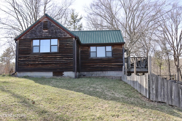 view of property exterior featuring a lawn, metal roof, and fence