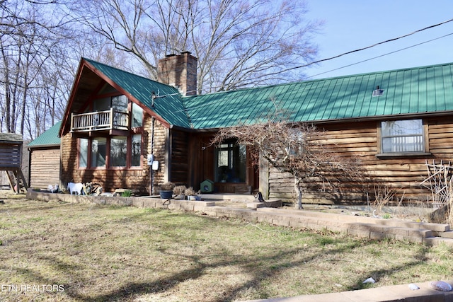 view of front of home with a balcony, a chimney, and metal roof