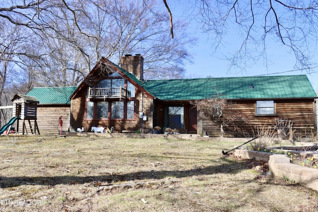 back of property with metal roof, a balcony, and a chimney