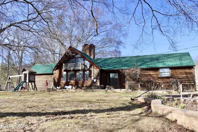 rear view of property with a chimney, metal roof, and a balcony