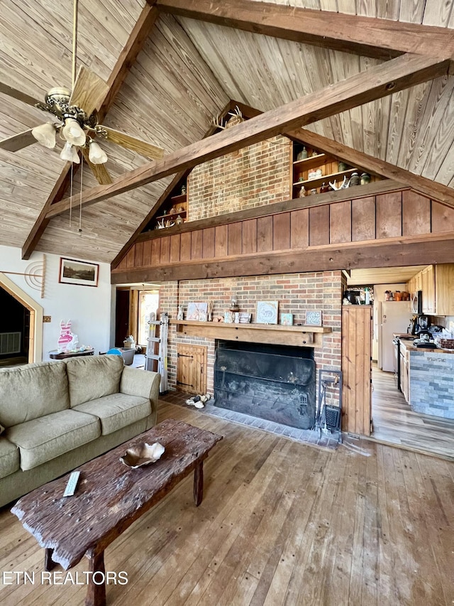 unfurnished living room with ceiling fan, wood ceiling, hardwood / wood-style floors, beam ceiling, and a fireplace