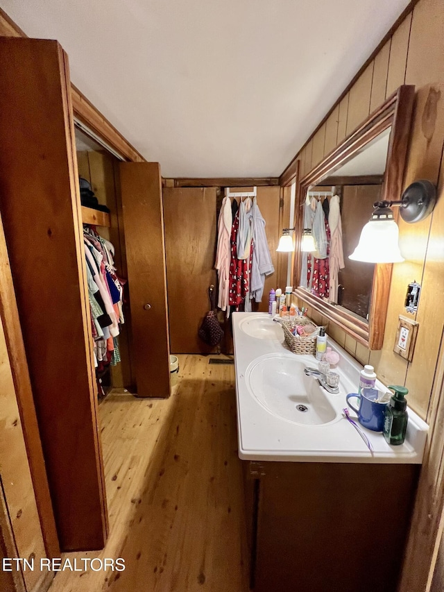 bathroom with vanity, wood finished floors, and wood walls