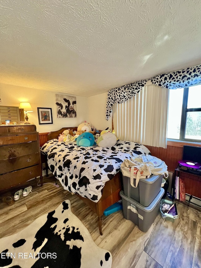 bedroom with a textured ceiling and wood finished floors