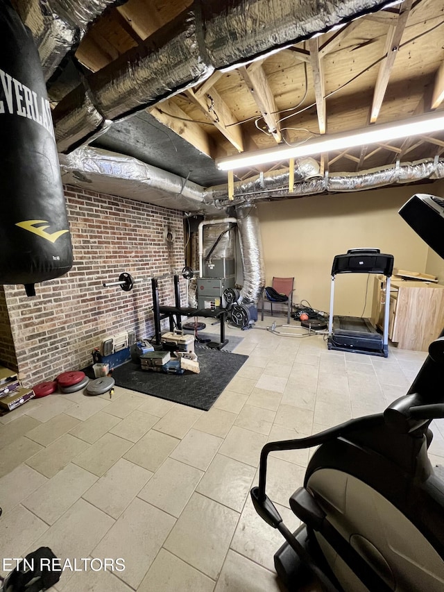 exercise area featuring tile patterned floors, heating unit, and brick wall