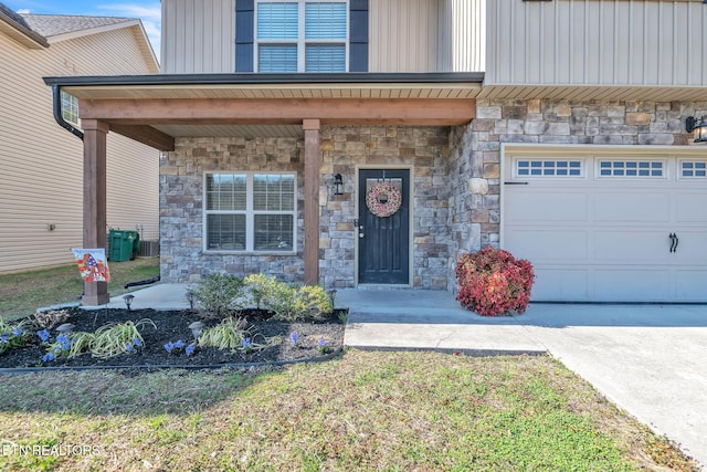 entrance to property featuring central AC unit, an attached garage, concrete driveway, stone siding, and board and batten siding