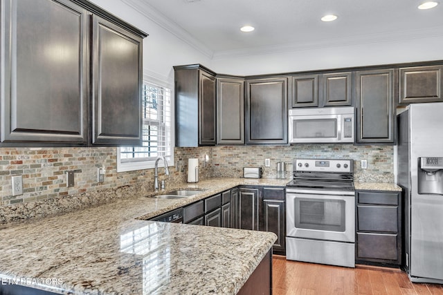 kitchen featuring a sink, light wood-style floors, appliances with stainless steel finishes, crown molding, and light stone countertops