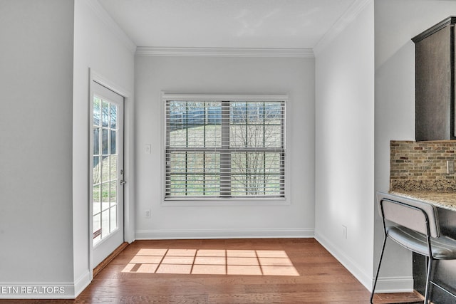 interior space with a healthy amount of sunlight, wood finished floors, and ornamental molding