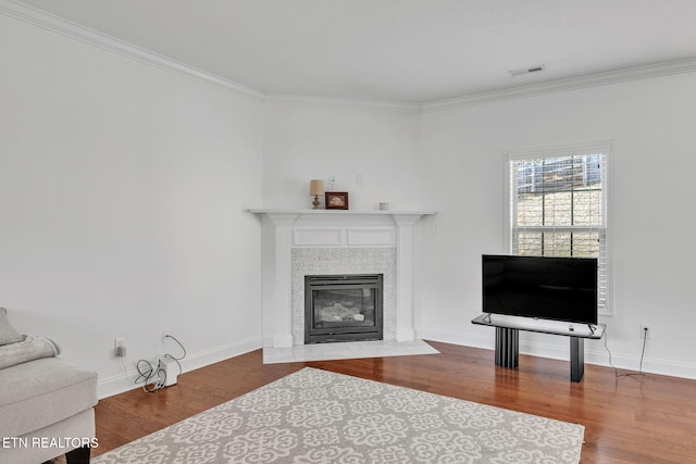 living area with visible vents, wood finished floors, a fireplace, and ornamental molding