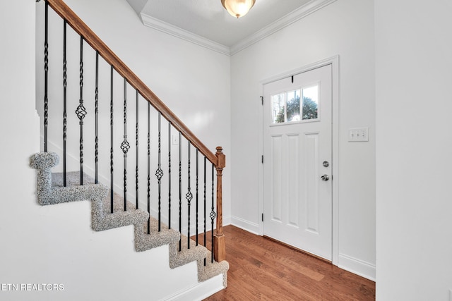 foyer entrance with stairs, wood finished floors, baseboards, and ornamental molding