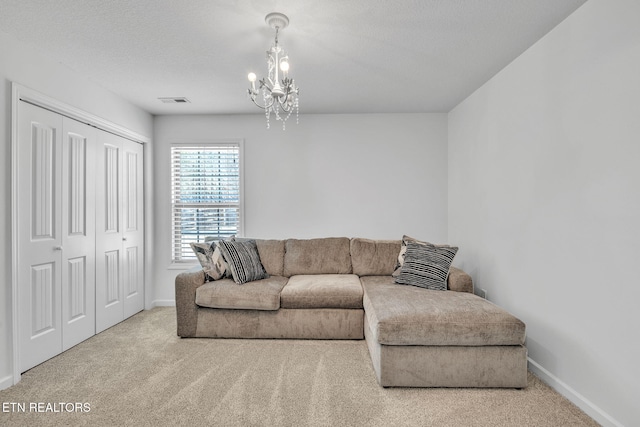 carpeted living room with visible vents, baseboards, a textured ceiling, and a chandelier