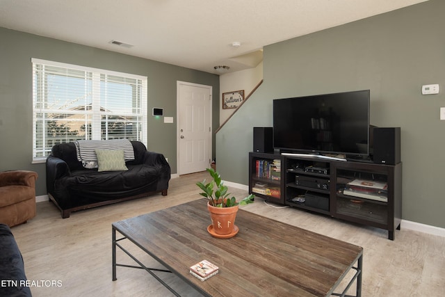 living room with visible vents, baseboards, and wood finished floors