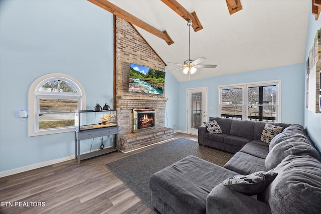 living area featuring beamed ceiling, high vaulted ceiling, wood finished floors, a fireplace, and baseboards