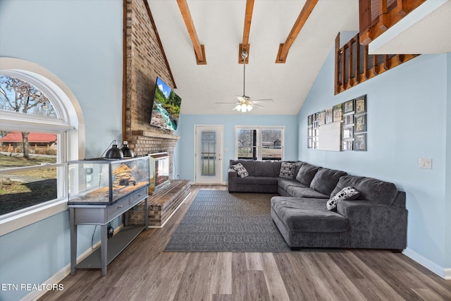 living area featuring wood finished floors, plenty of natural light, a fireplace, and high vaulted ceiling