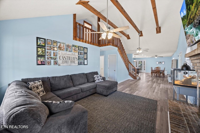 living area featuring baseboards, stairway, beamed ceiling, wood finished floors, and high vaulted ceiling