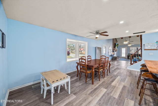 dining space with baseboards, stairway, vaulted ceiling, wood finished floors, and a textured ceiling