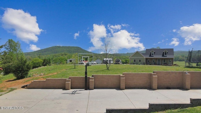 view of property's community with a trampoline, a lawn, and a mountain view