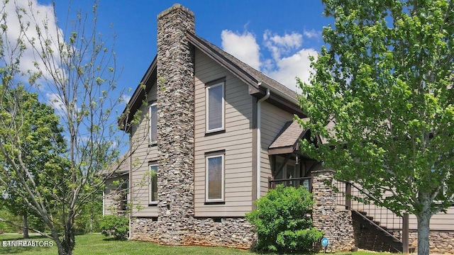 view of property exterior with a lawn, stairway, a shingled roof, crawl space, and a chimney