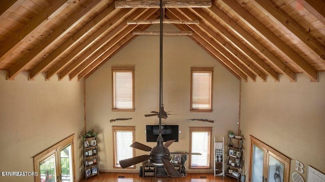 unfurnished living room featuring lofted ceiling with beams, a ceiling fan, and a wealth of natural light