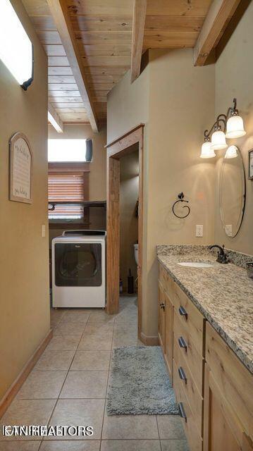 bathroom featuring beamed ceiling, wood ceiling, vanity, tile patterned floors, and washer / clothes dryer