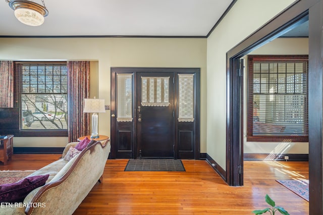 foyer with crown molding, wood finished floors, and baseboards