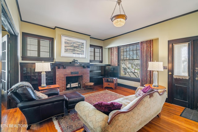 living room featuring a brick fireplace, wood finished floors, and crown molding