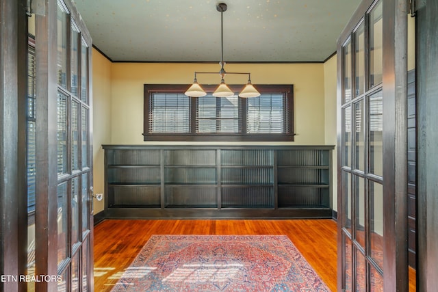 unfurnished dining area featuring crown molding, wood finished floors, and french doors