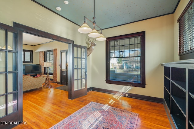 interior space featuring wood finished floors, baseboards, and ornamental molding