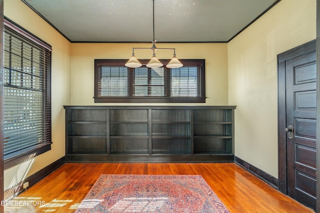 unfurnished dining area with baseboards, wood finished floors, and ornamental molding