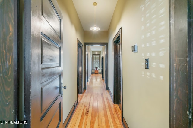 corridor featuring light wood-style flooring and baseboards