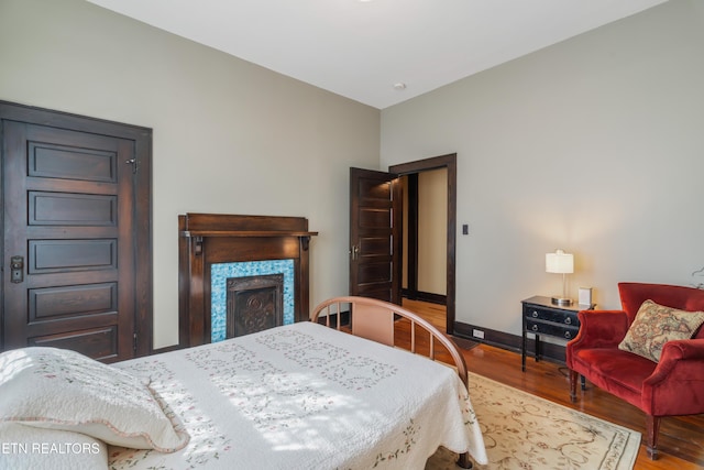 bedroom featuring baseboards, wood finished floors, and a fireplace