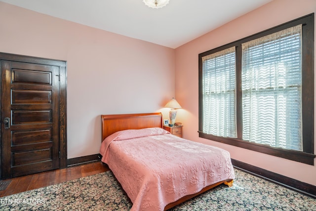 bedroom with multiple windows, baseboards, and wood finished floors