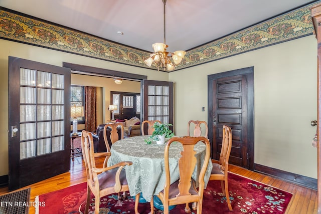 dining space with baseboards, wood-type flooring, and an inviting chandelier