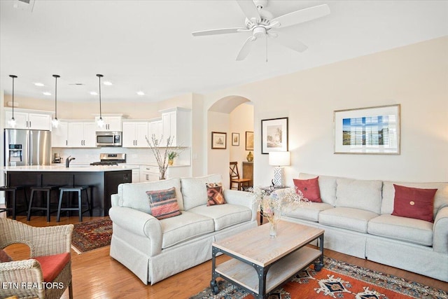 living room with recessed lighting, arched walkways, wood finished floors, and a ceiling fan