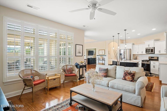 living room with ceiling fan, visible vents, a healthy amount of sunlight, and wood finished floors