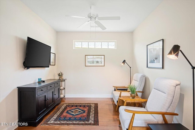 sitting room with ceiling fan, baseboards, and wood finished floors