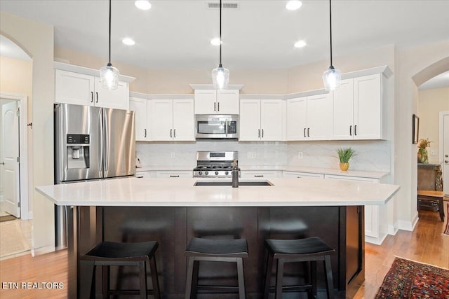 kitchen featuring white cabinetry, a kitchen bar, arched walkways, and appliances with stainless steel finishes