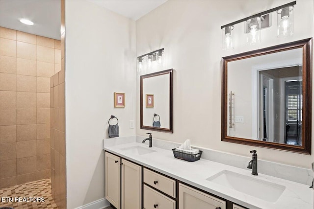 full bath featuring double vanity, a tile shower, and a sink