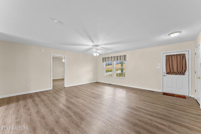 unfurnished living room featuring wood finished floors, baseboards, and ceiling fan