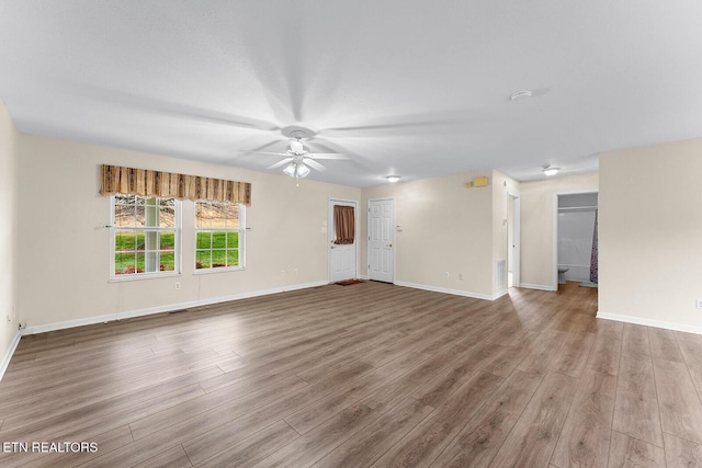 unfurnished living room featuring visible vents, baseboards, a ceiling fan, and wood finished floors