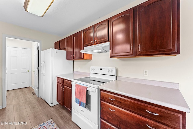 kitchen with under cabinet range hood, light wood finished floors, white appliances, and light countertops