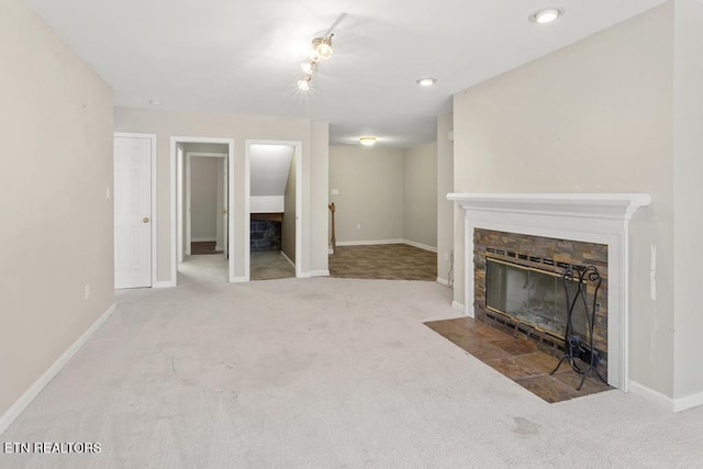 unfurnished living room featuring baseboards, carpet floors, and a stone fireplace