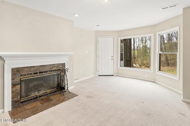 unfurnished living room featuring visible vents, carpet flooring, a fireplace, and baseboards