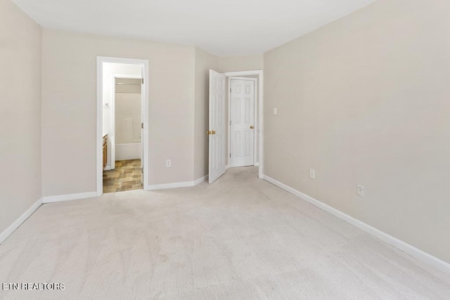 unfurnished bedroom featuring baseboards, carpet floors, and ensuite bathroom