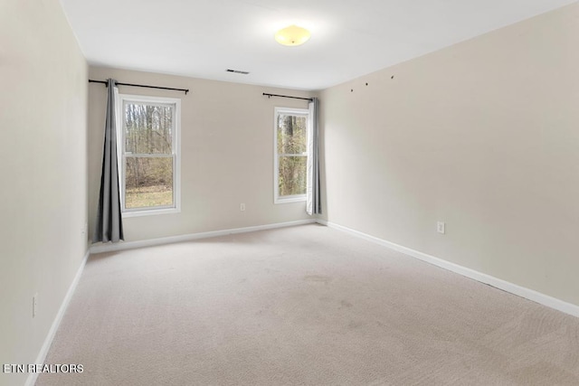 empty room featuring visible vents, baseboards, and light carpet