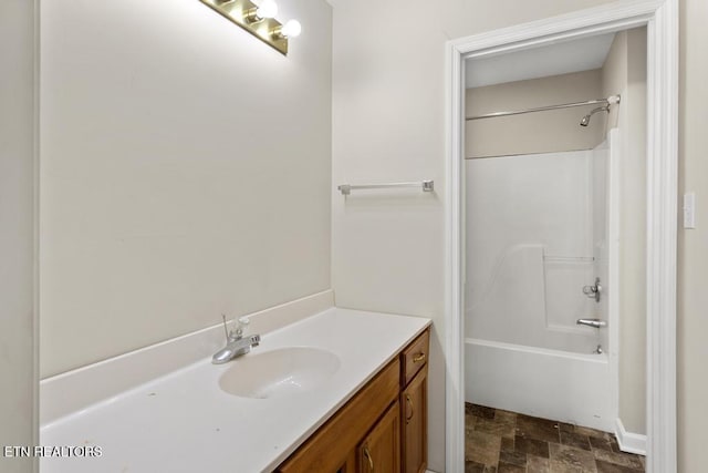 full bath featuring shower / bathing tub combination, stone finish flooring, and vanity