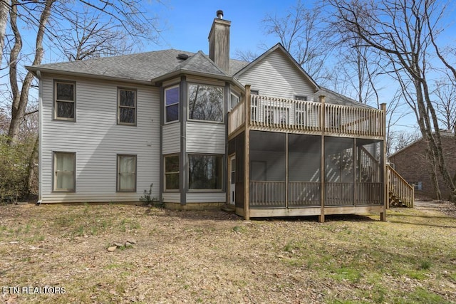 rear view of property with a shingled roof, a sunroom, and a chimney