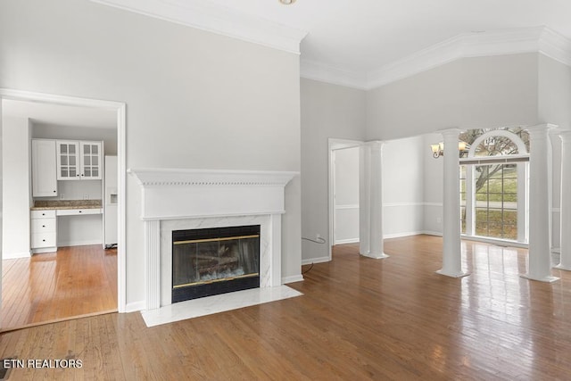 unfurnished living room with ornamental molding, wood finished floors, a high end fireplace, decorative columns, and built in study area