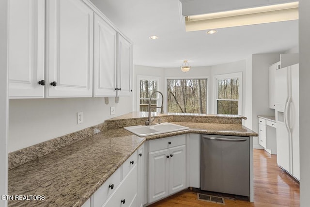 kitchen with visible vents, a sink, stainless steel dishwasher, white refrigerator with ice dispenser, and a peninsula