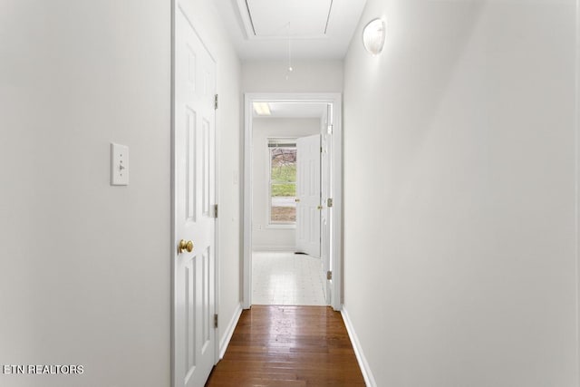 corridor with attic access, baseboards, and dark wood-type flooring