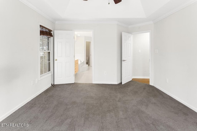 unfurnished bedroom featuring ensuite bath, a raised ceiling, baseboards, and carpet floors